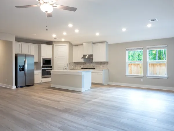 a large white kitchen with kitchen island a stove a sink cabinets and wooden floor