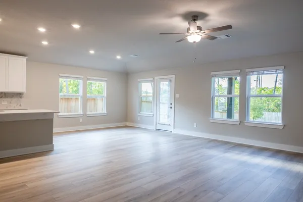 a view of an empty room with a window and wooden floor
