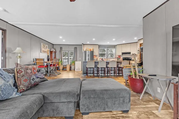 a living room with furniture kitchen view and a large window