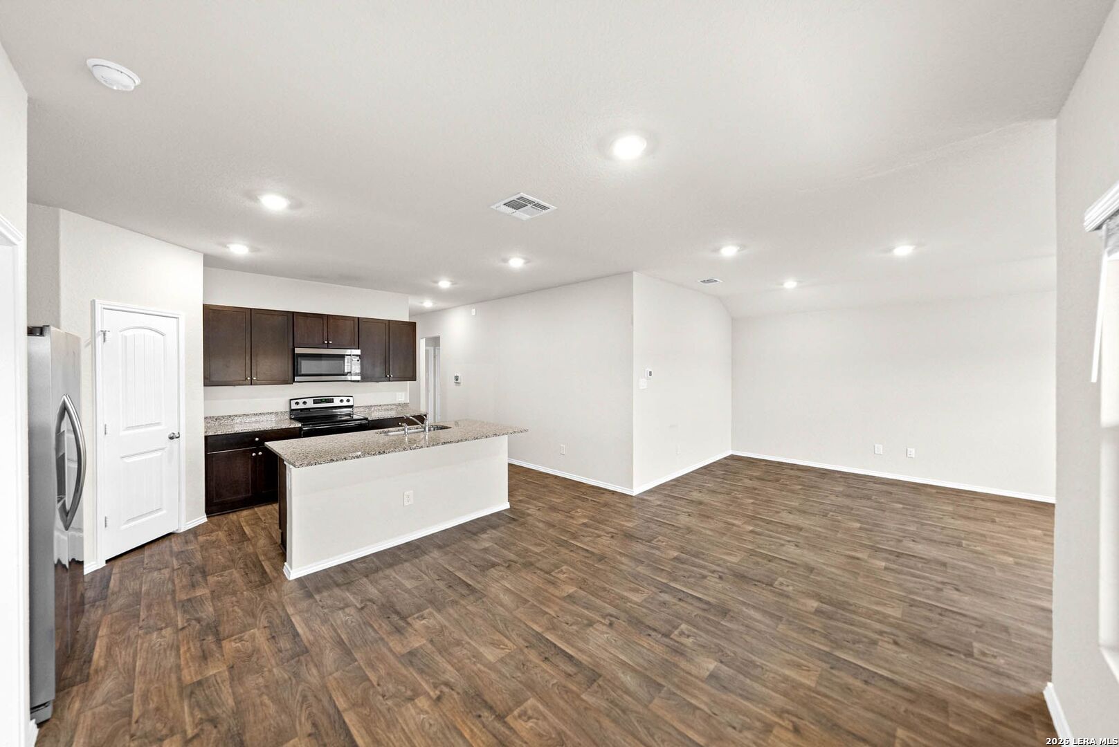 917 Chachalaca Court Seguin, TX 78155 - Photo 15 of 44 a large white kitchen with kitchen island a sink dishwasher a refrigerator and a stove with wooden floor