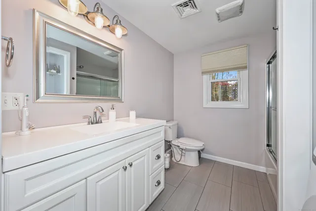 a bathroom with a toilet a sink a mirror and vanity