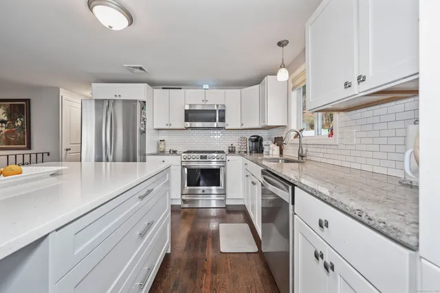a kitchen with kitchen island granite countertop a sink appliances cabinets and a counter top space
