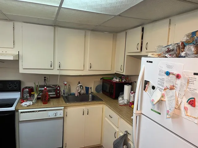 a kitchen with a refrigerator and white cabinets