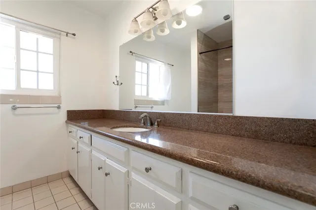 a spacious bathroom with a granite countertop sink a mirror and a shower