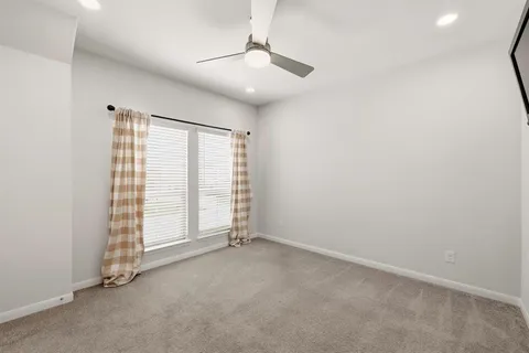 an empty room with windows and ceiling fan