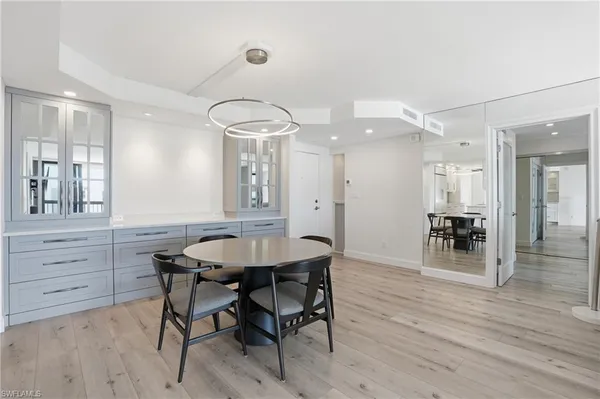 a dining room with wooden floor a chandelier a wooden table and chairs