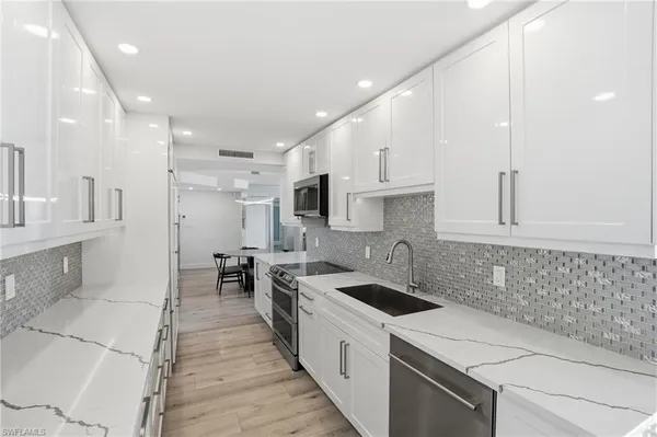 a kitchen with a sink a counter top space stainless steel appliances and cabinets