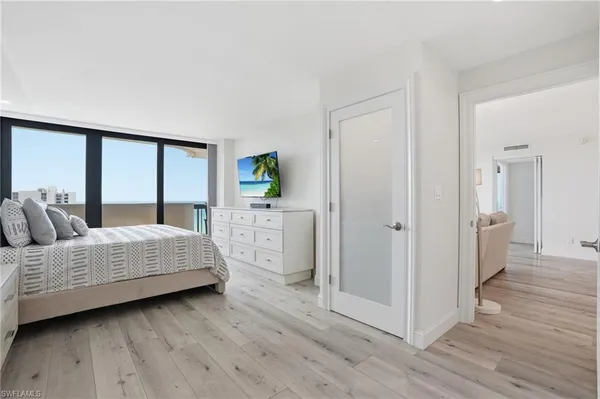 a bedroom with a bed a mirror and a hardwood