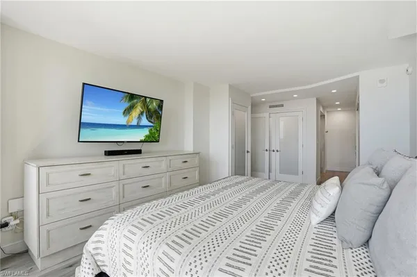 a bedroom with a bed and a flat screen tv in white dresser