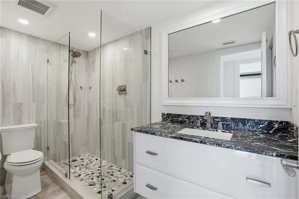 a bathroom with a granite countertop sink toilet and shower