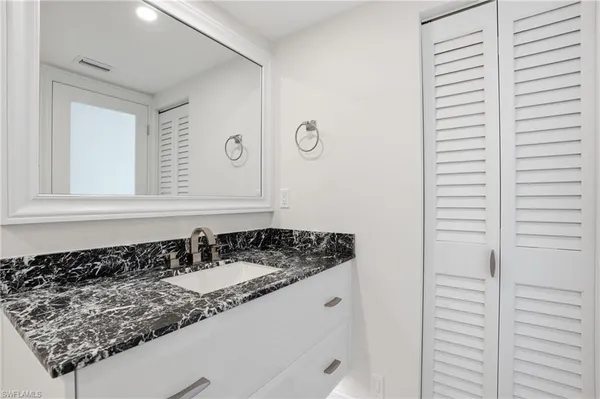 a bathroom with a granite countertop sink and a mirror