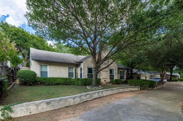 a front view of a house with a garden and trees