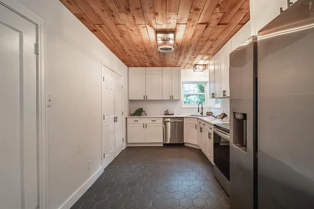a kitchen with a sink stainless steel appliances cabinets and a window