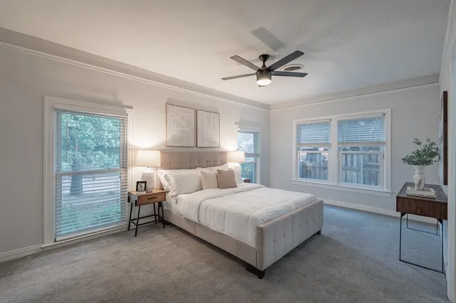 a bedroom with a bed a table and windows