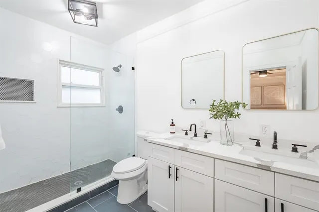 a bathroom with a double vanity sink toilet and a mirror