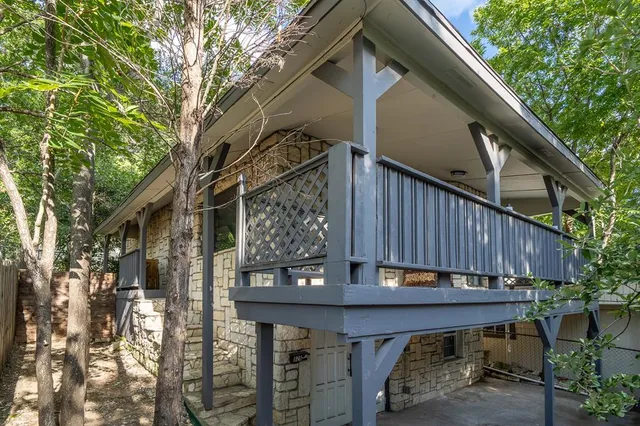 a backyard of a house with wooden fence and large trees