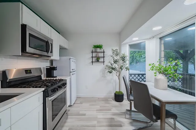 a kitchen with stainless steel appliances a stove a microwave a sink a refrigerator dining table and chairs