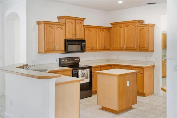 an empty room with chandelier fan and windows