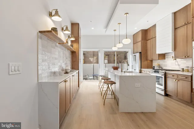 a kitchen with stainless steel appliances kitchen island granite countertop a refrigerator a oven a sink and a dining table with wooden floor