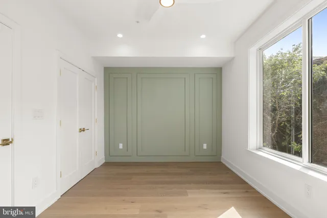 a view of an empty room with window and wooden floor