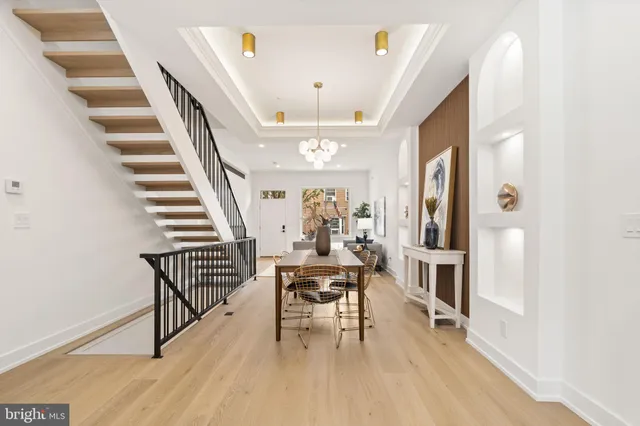 a view of a hallway with wooden floor staircase and a living room
