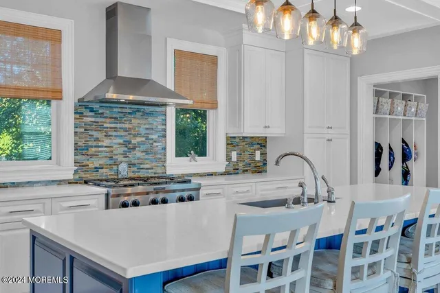 a kitchen with a stove a sink a kitchen island with a dining table and chairs