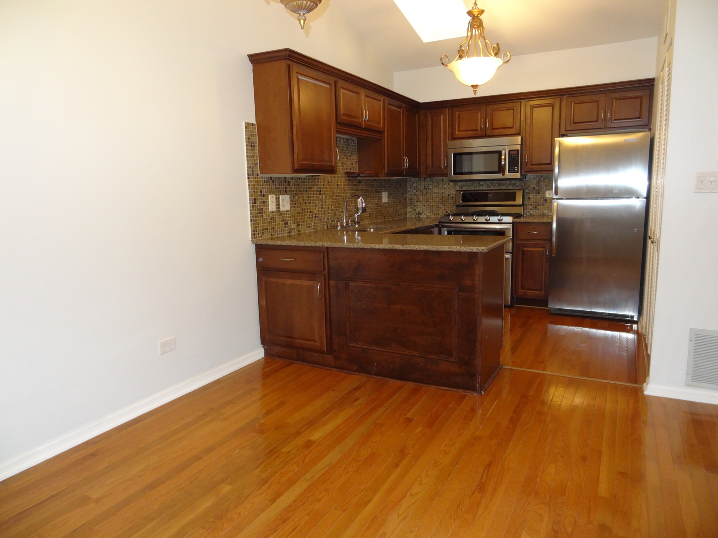 450 Bridle Trail, Unit 450 Wheeling, IL 60090 - Photo 7 of 15 a kitchen with stainless steel appliances granite countertop a refrigerator a stove and a sink with wooden floor