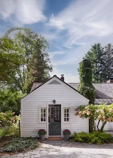 a view of a white house next to a yard and road