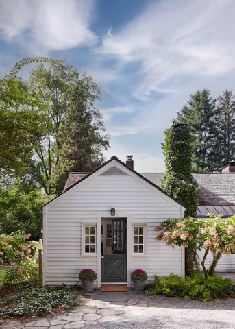 a view of a white house next to a yard and road