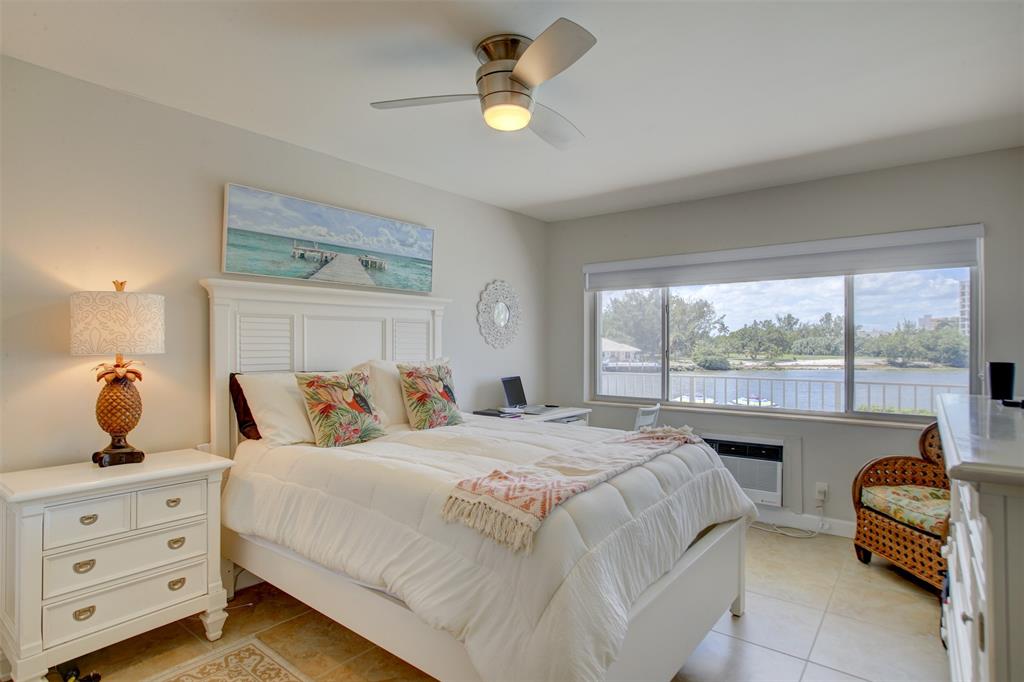 999 North Riverside Drive, Unit 10 Pompano Beach, FL 33062 - Photo 9 of 14 a bedroom with a bed a chandelier and a window