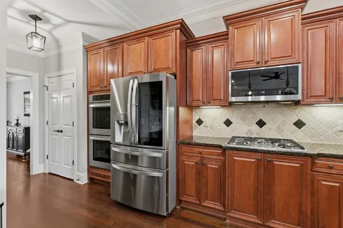 a kitchen with stainless steel appliances granite countertop a refrigerator and a stove top oven