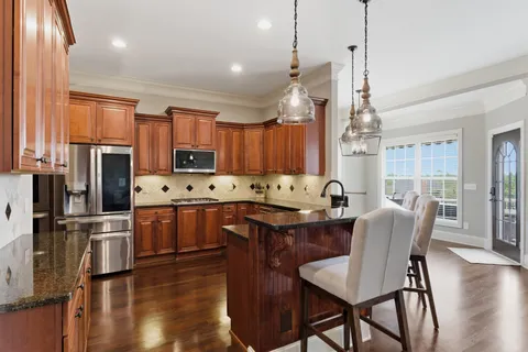 a kitchen with stainless steel appliances granite countertop a table chairs refrigerator and microwave