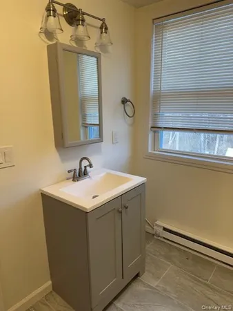 a bathroom with a sink a mirror and next to a window