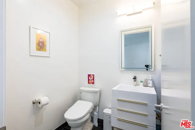 a bathroom with a toilet sink vanity and mirror