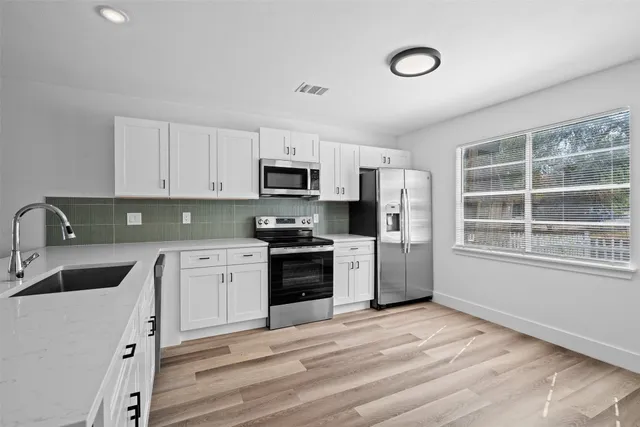 a kitchen with granite countertop white cabinets and stainless steel appliances