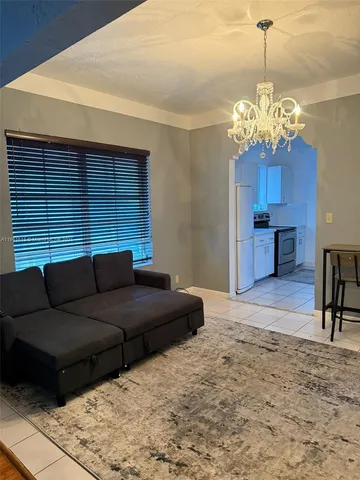 a living room with furniture a dining table and a chandelier