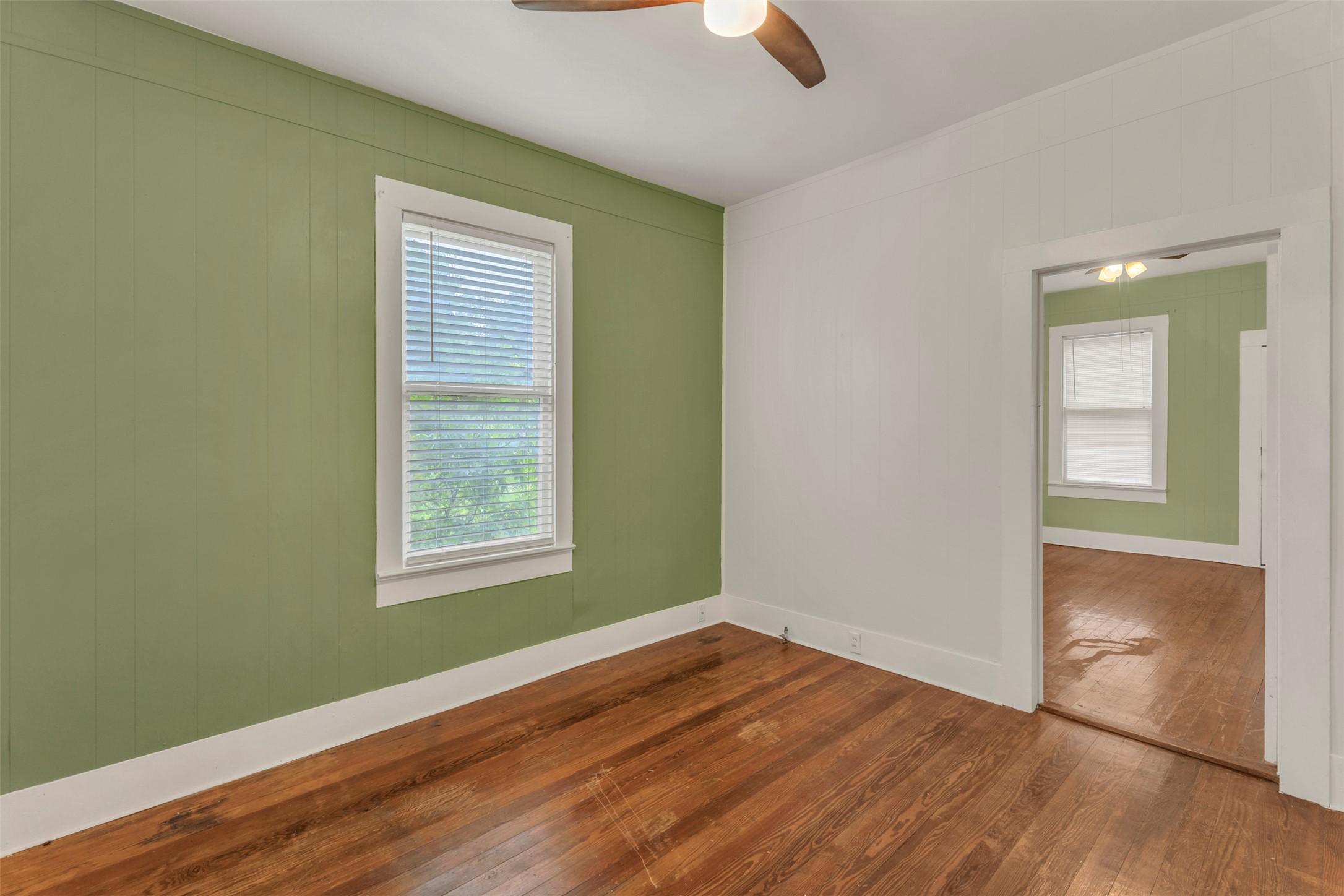 1002 Washburn Street Taylor, TX 76574 - Photo 17 of 29 This room features a window with blinds, wood paneling on one wall, and hardwood floors