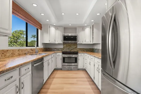 a large kitchen with stainless steel appliances granite countertop a refrigerator and a stove top oven