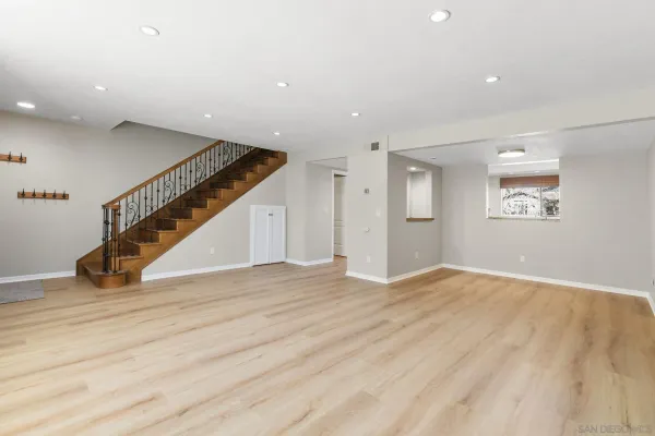 a view of an empty room with wooden floor and stairs