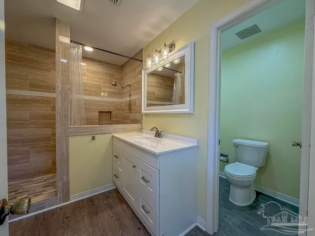 a bathroom with a granite countertop sink toilet and mirror