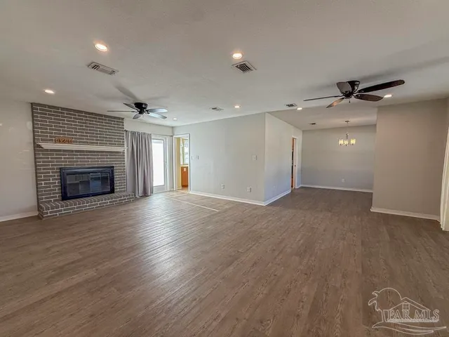 an empty room with wooden floor fireplace and windows
