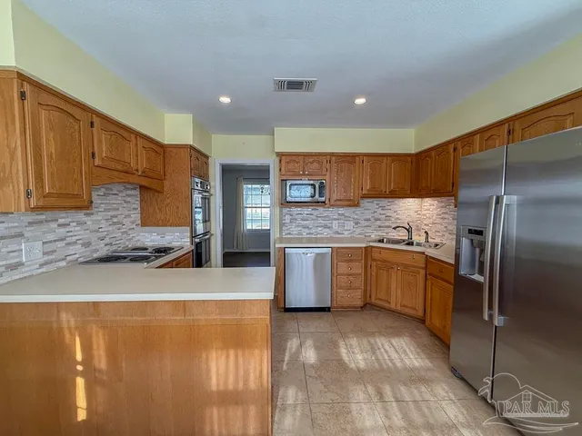 a large kitchen with a large counter top stainless steel appliances and cabinets