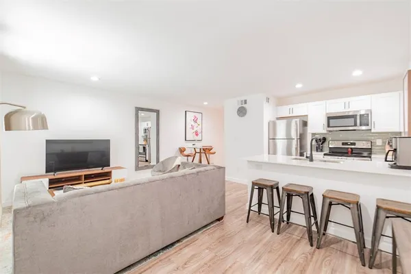 a living room with furniture a flat screen tv and kitchen view