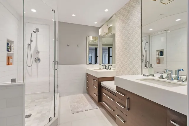 a bathroom with a double vanity sink mirror and shower