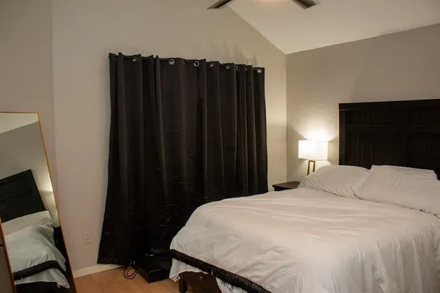 a bedroom with a bed a flat tv screen and a chair