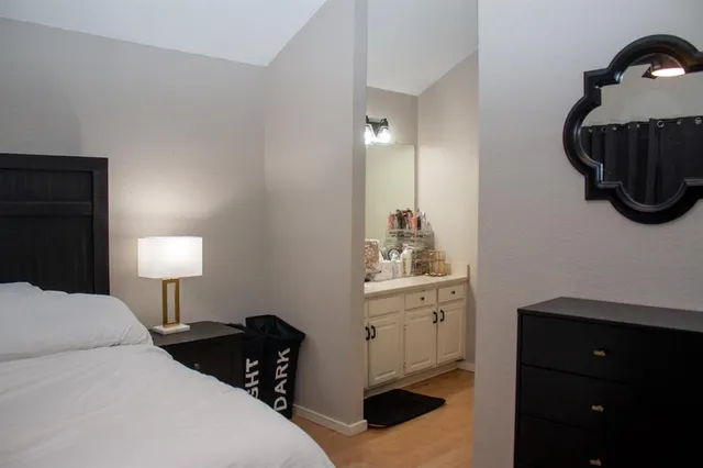 a bedroom with a bed and a lamp on dresser