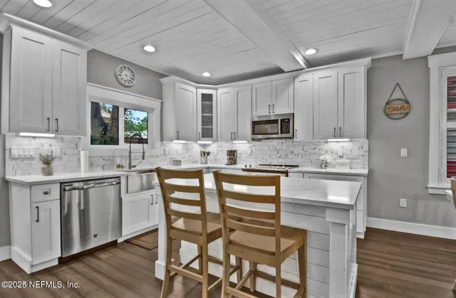 a kitchen with granite countertop white cabinets and stainless steel appliances