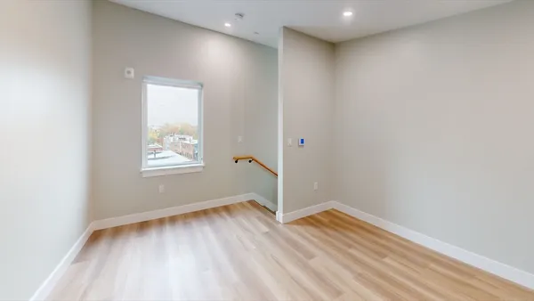 an empty room with wooden floor and windows