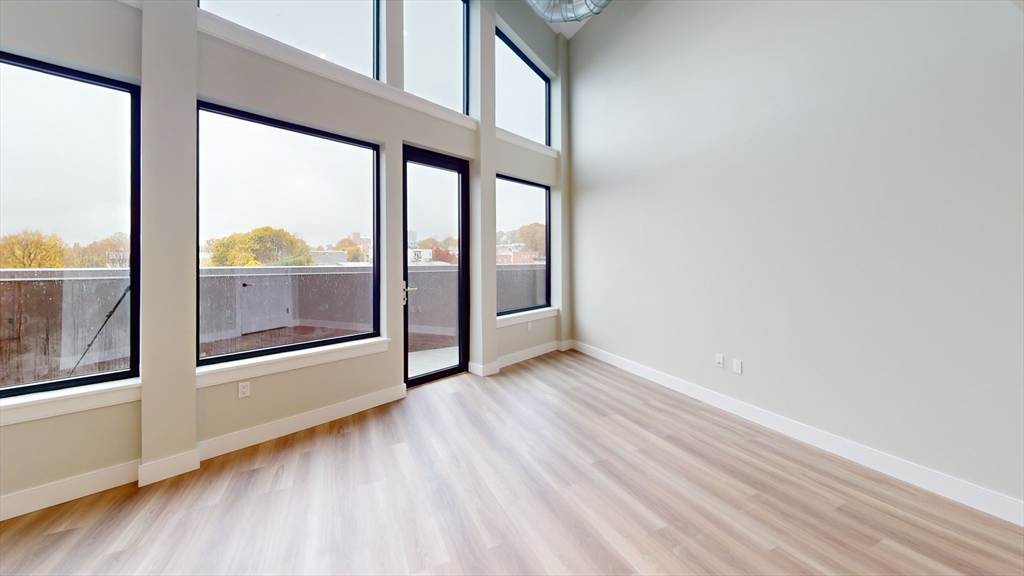 211 Green Street, Unit 509 Boston, MA 02130 - Photo 3 of 20 an empty room with wooden floor and door