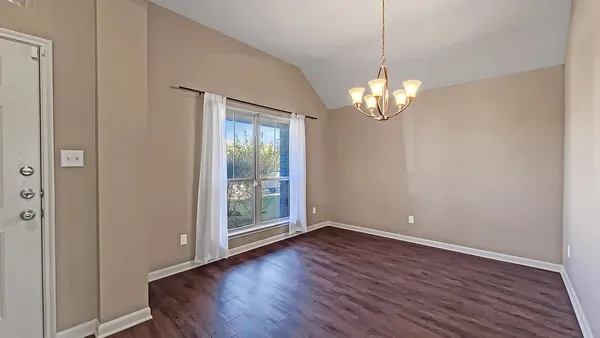 a view of a room with wooden floor chandelier and windows